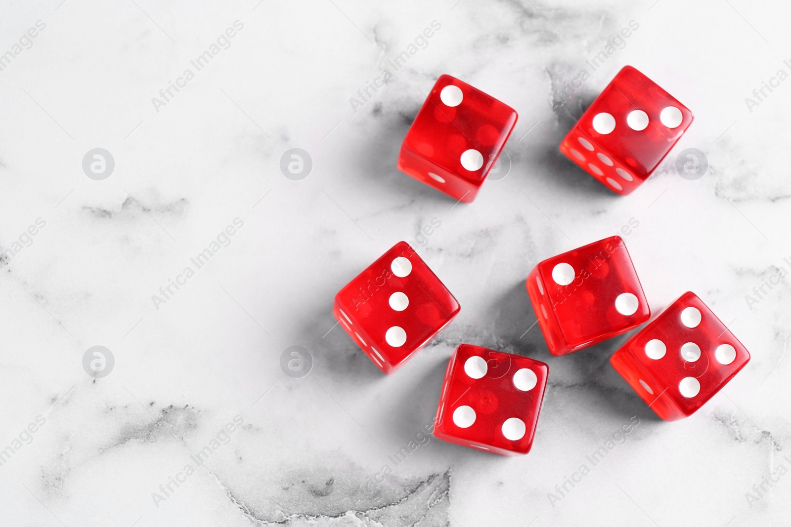 Photo of Many red game dices on white marble table, flat lay. Space for text