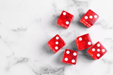 Many red game dices on white marble table, flat lay. Space for text