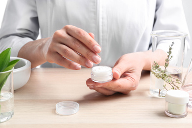 Photo of Woman with cream at table in cosmetic laboratory, closeup