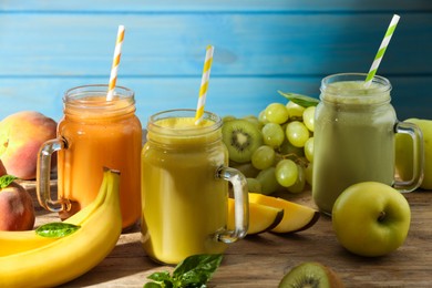 Photo of Mason jars of different tasty smoothies and fresh ingredients on wooden table