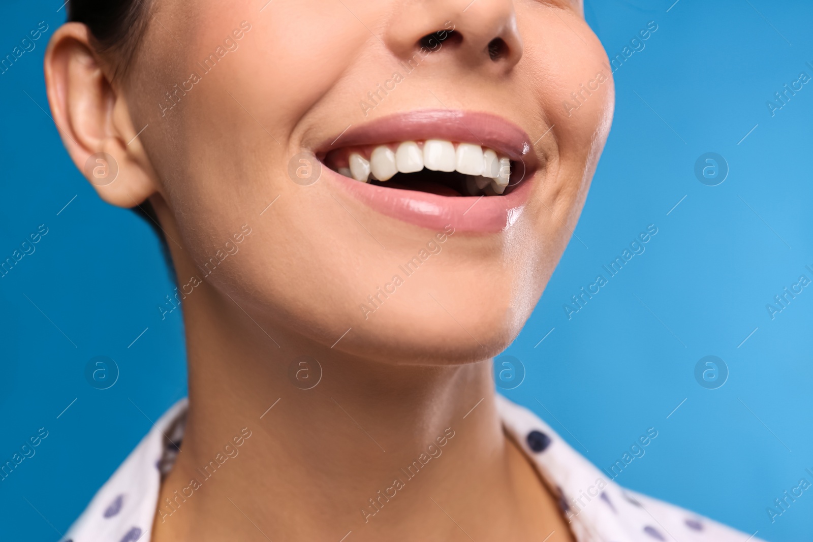 Photo of Young woman with beautiful smile on blue background, closeup. Cosmetic dentistry