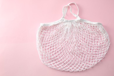 Photo of White string bag on pink background, top view. Space for text