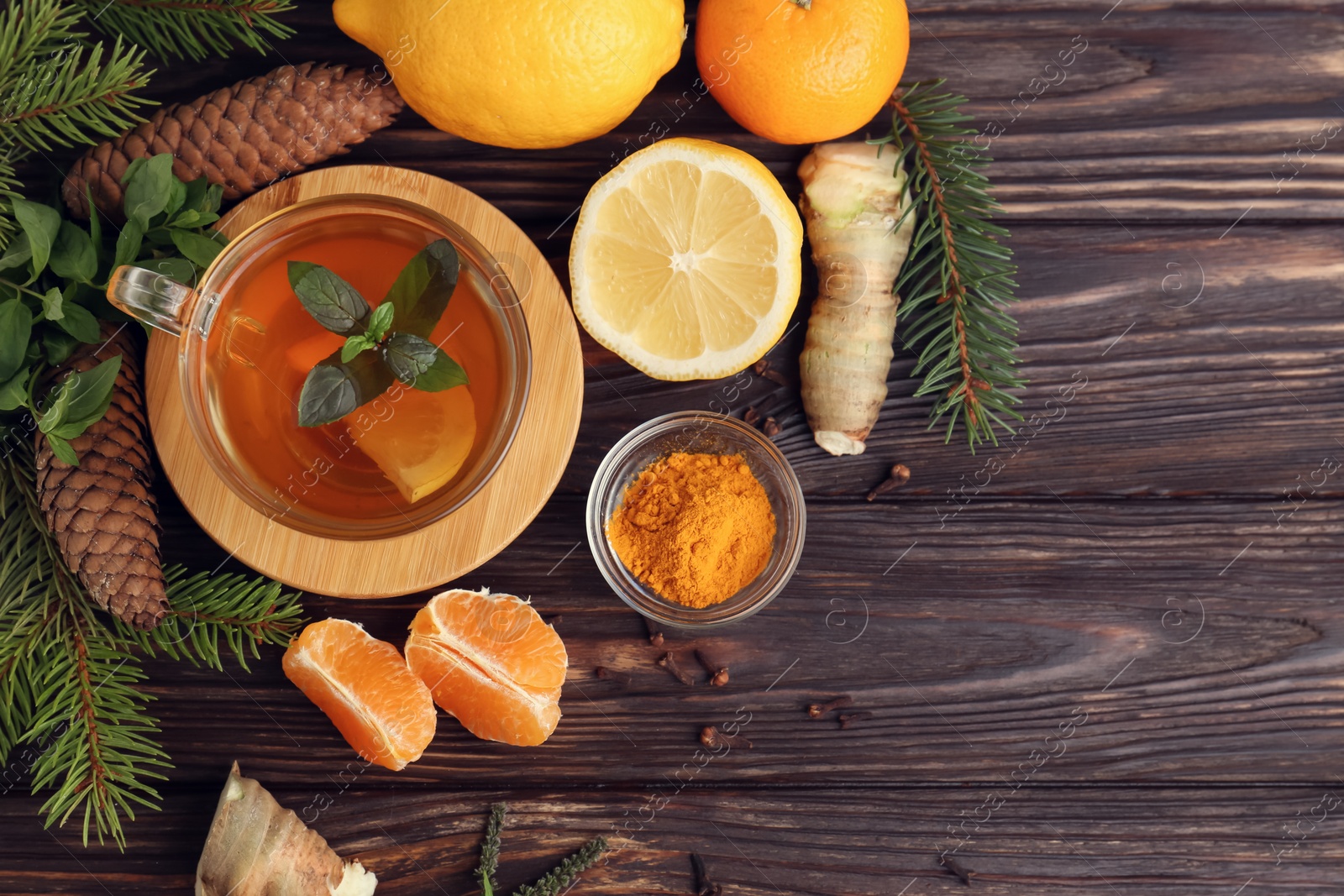 Photo of Flat lay composition with glass cup of delicious immunity boosting tea and ingredients on wooden table. Space for text