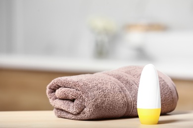 Photo of Roll-on deodorant and clean towel on table in bathroom