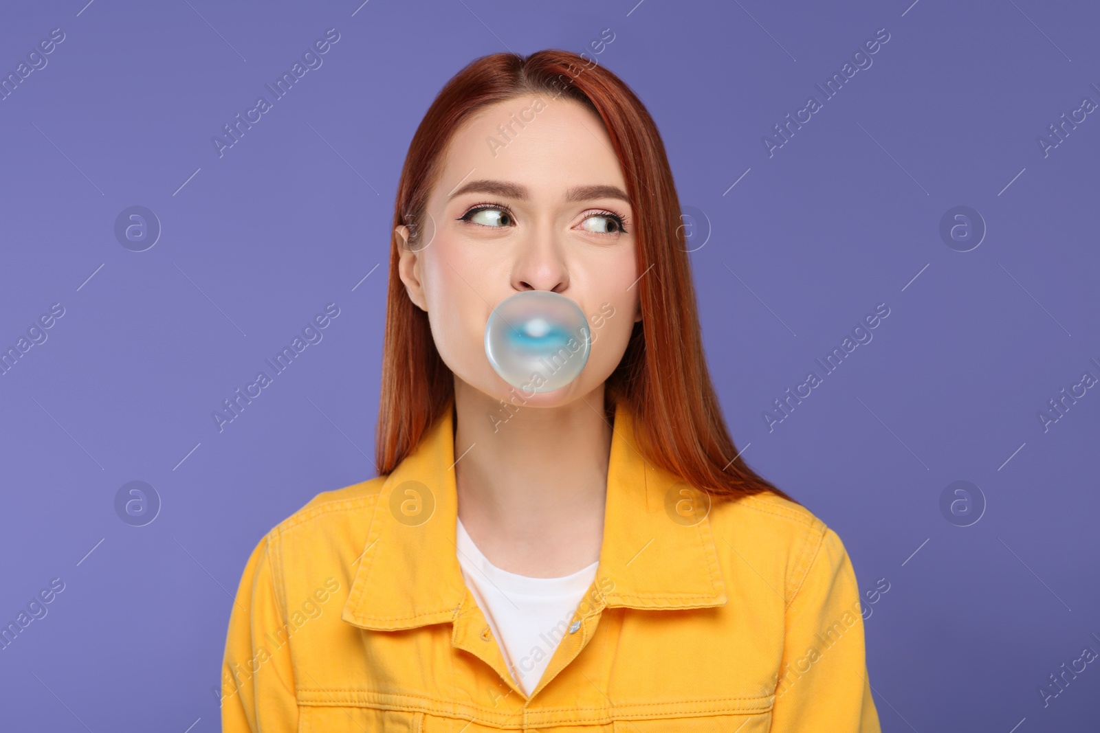 Photo of Beautiful woman blowing bubble gum on purple background