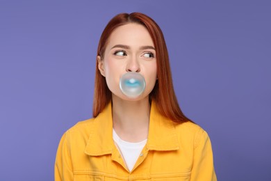 Photo of Beautiful woman blowing bubble gum on purple background