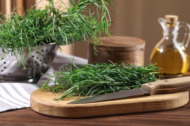 Photo of Board with fresh tarragon leaves and knife on wooden table