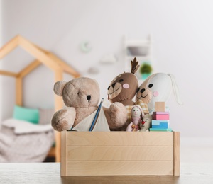 Set of different cute toys on wooden table in children's room