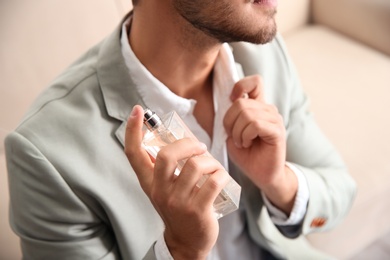 Photo of Businessman applying perfume on blurred background, closeup