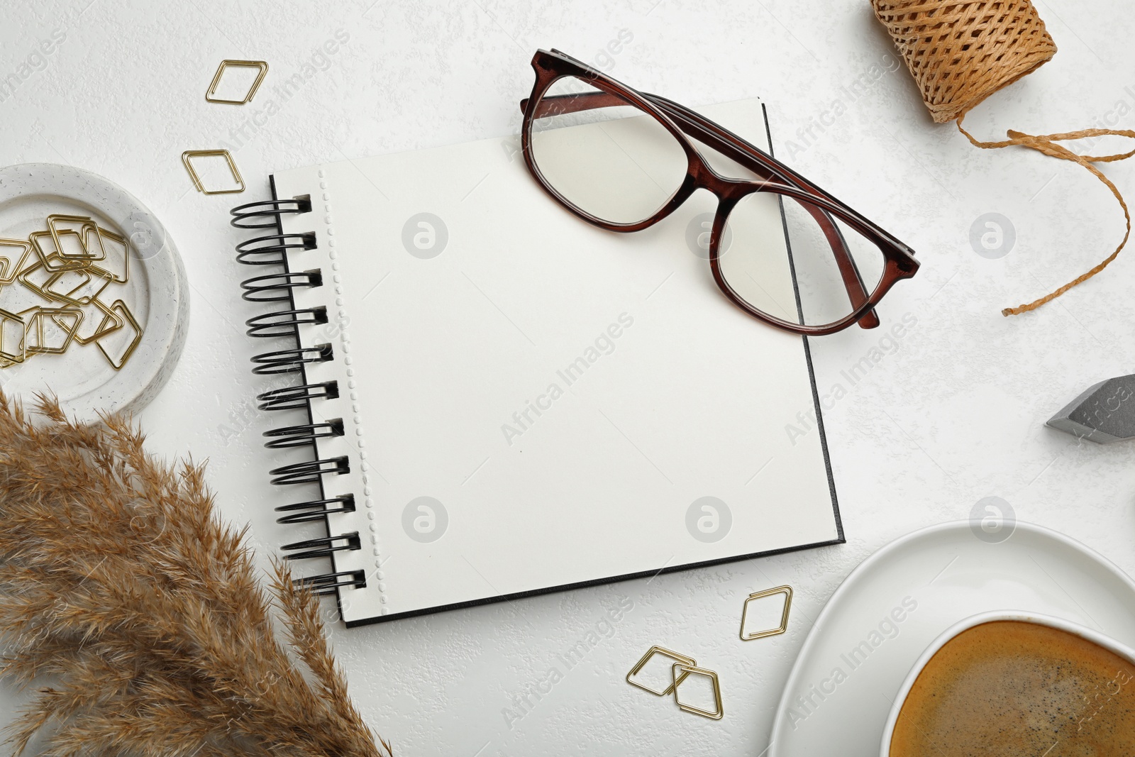 Photo of Flat lay composition with stylish spiral notebook and glasses on white table