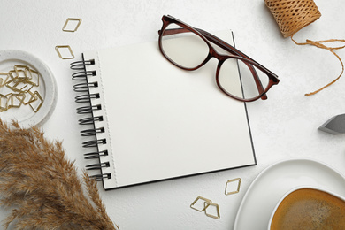 Flat lay composition with stylish spiral notebook and glasses on white table