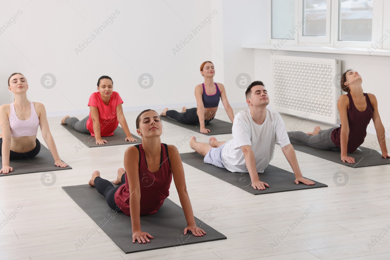 Photo of Group of people practicing yoga on mats indoors