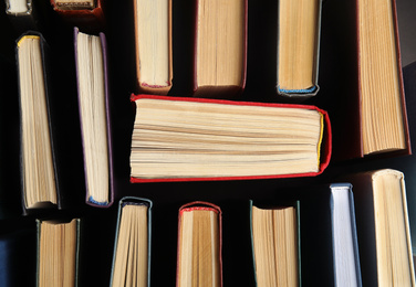 Photo of Many different hardcover books on dark background, top view