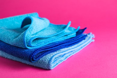 Stack of blue microfiber cloths on pink background, closeup