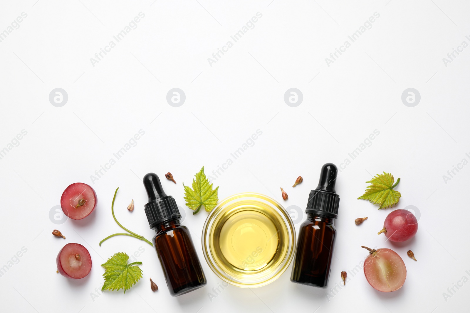 Photo of Composition with bottles and bowl of natural grape seed oil on white background, top view. Organic cosmetic