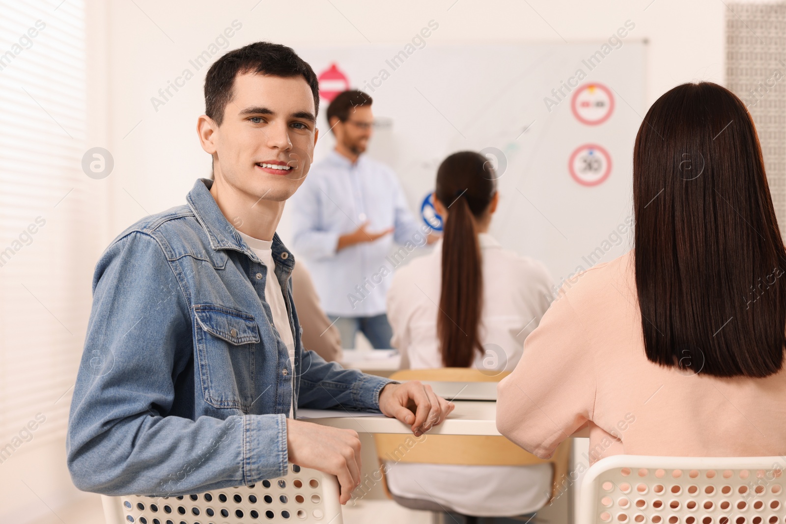 Photo of Smiling man at desk in class during lesson in driving school