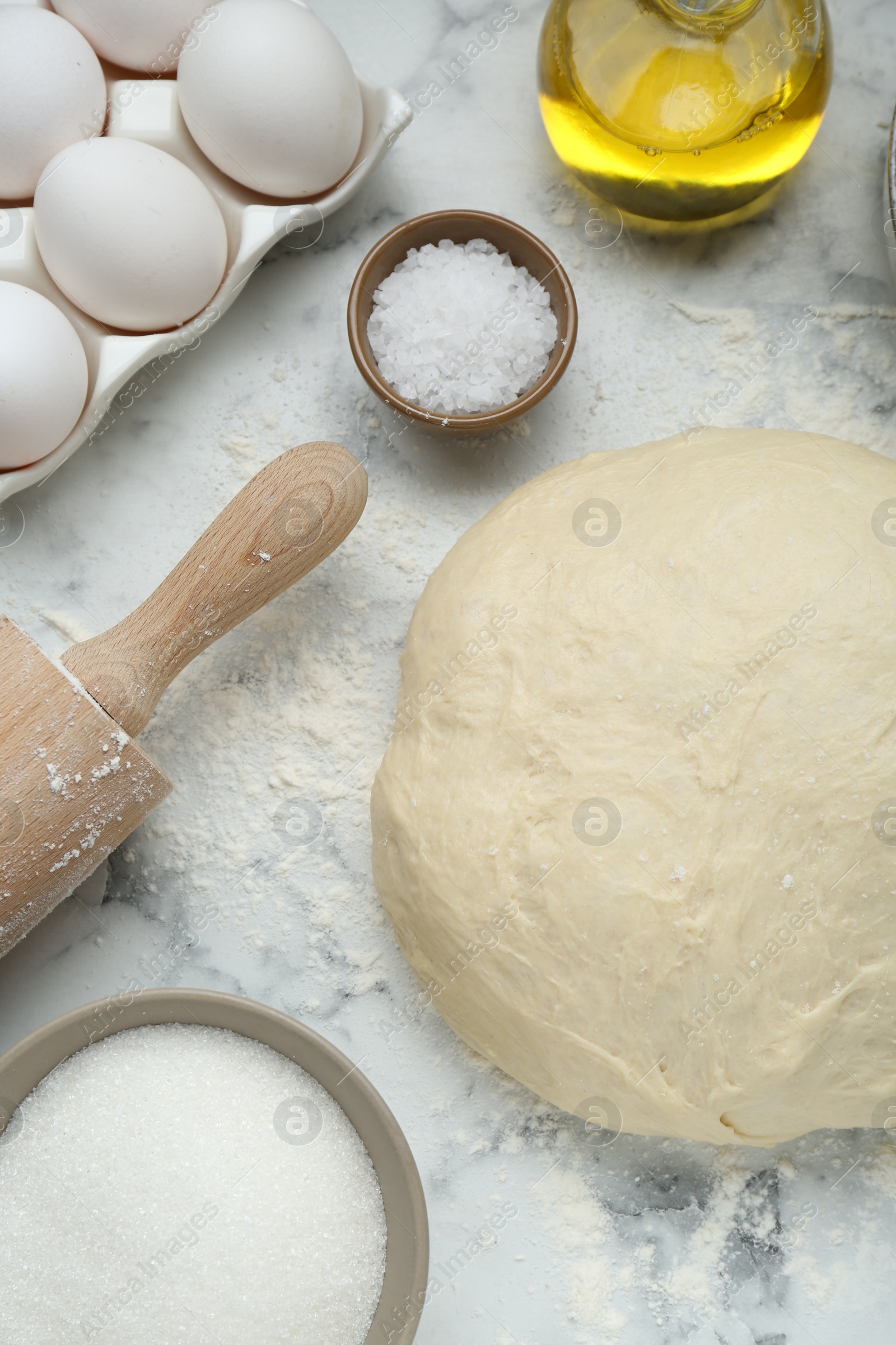 Photo of Fresh yeast dough and ingredients on white marble table, flat lay