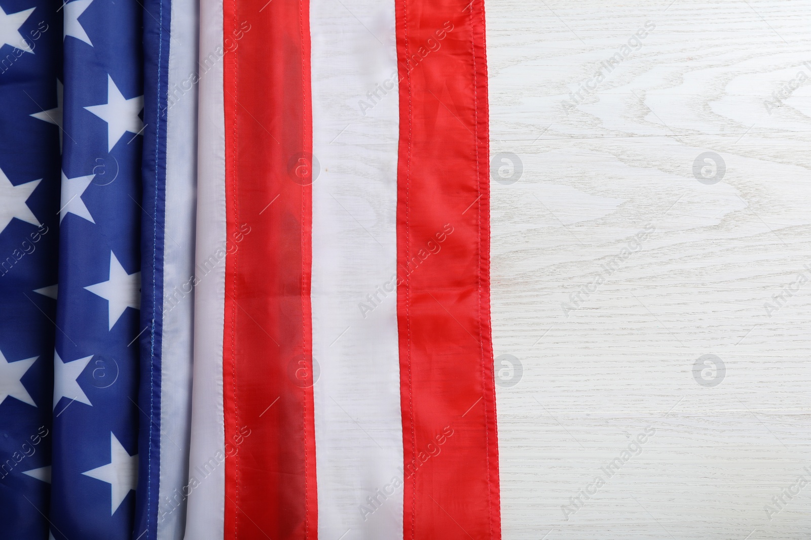 Photo of American flag on white wooden table, top view. Space for text