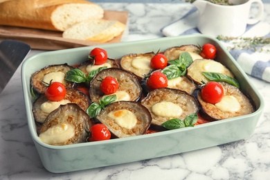 Photo of Baked eggplant with tomatoes, cheese and basil on marble table