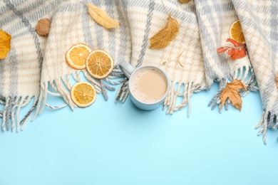 Flat lay composition with coffee and warm plaid on light blue background, space for text