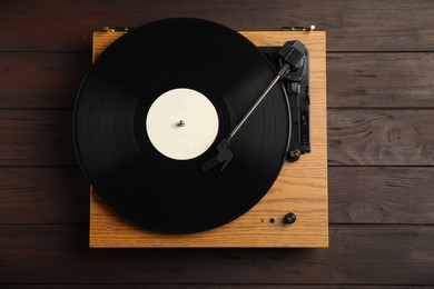 Photo of Turntable with vintage vinyl record on wooden background, top view