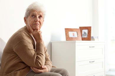 Photo of Thoughtful elderly woman at home. Space for text