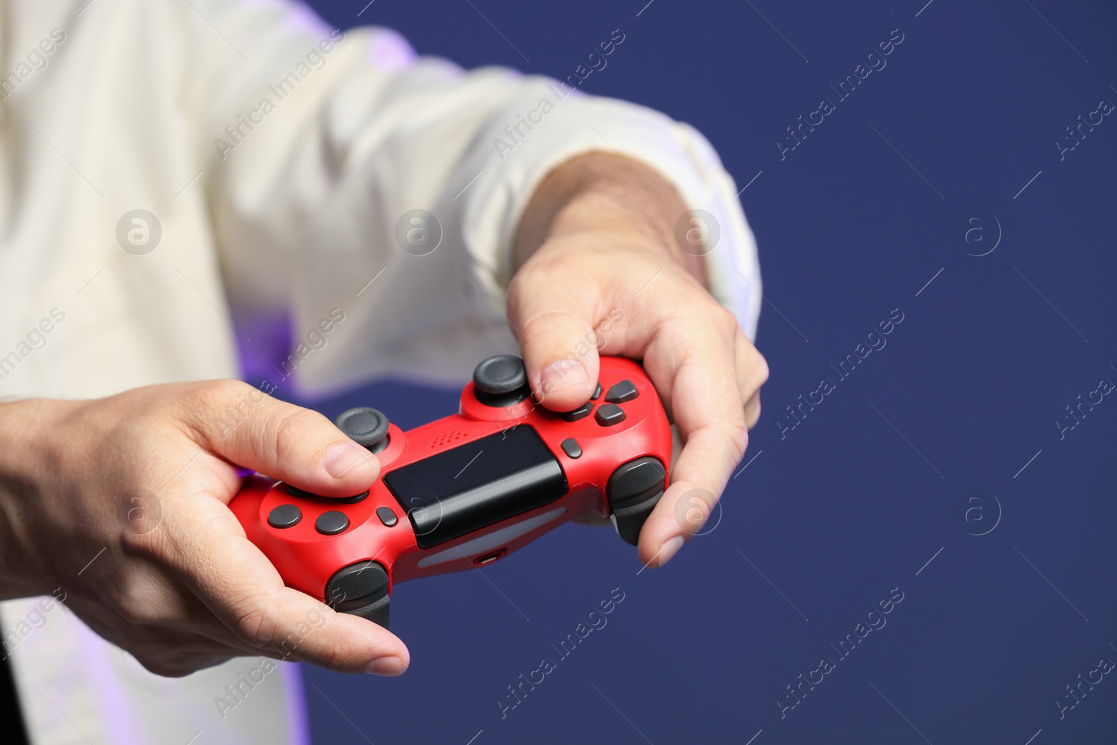 Photo of Man playing video game with controller on dark blue background, closeup. Space for text