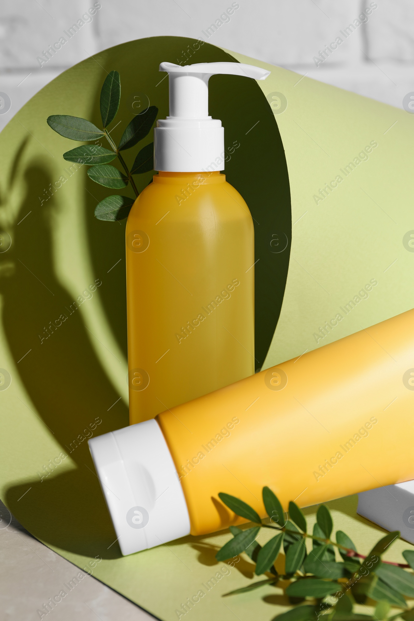 Photo of Different cleansers and leaves on grey table, space for text. Cosmetic product