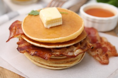 Delicious pancakes with bacon, butter and honey on table, closeup