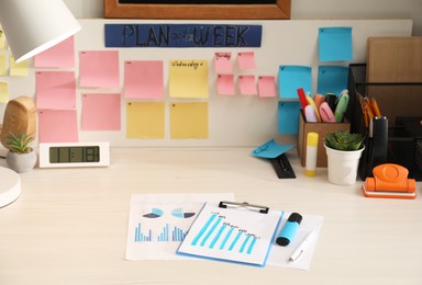 Photo of Business process planning and optimization. Workplace with lamp, colorful paper notes and other stationery on white wooden table