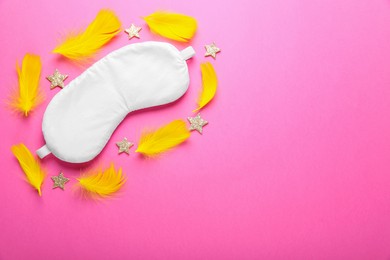 Photo of Soft sleep mask, decorative stars and yellow feather on pink background, flat lay. Space for text