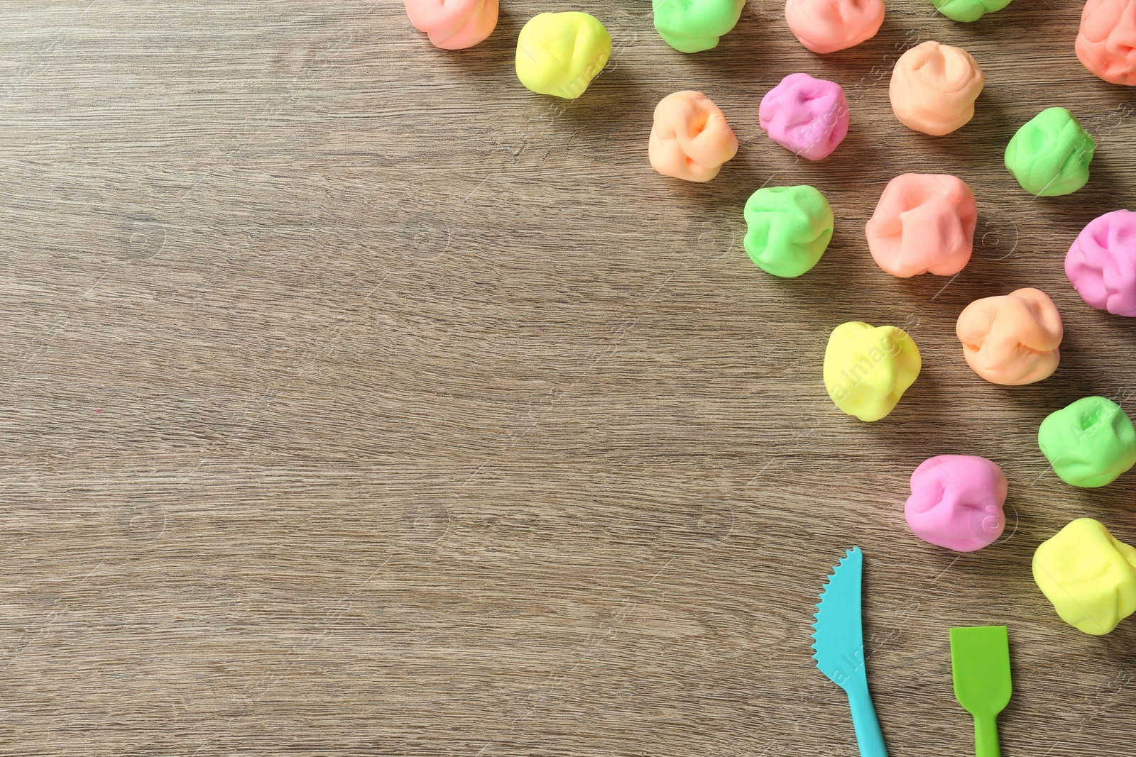 Photo of Different color play dough and tools on wooden table, flat lay. Space for text