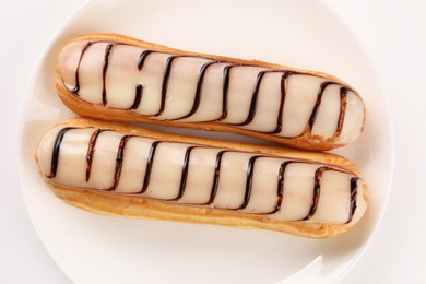 Delicious eclairs covered with glaze on white background, top view