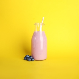 Tasty fresh milk shake and blueberries on yellow background