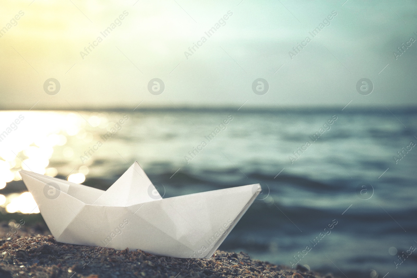 Image of White paper boat near river on sunny day. Retro photo effect 
