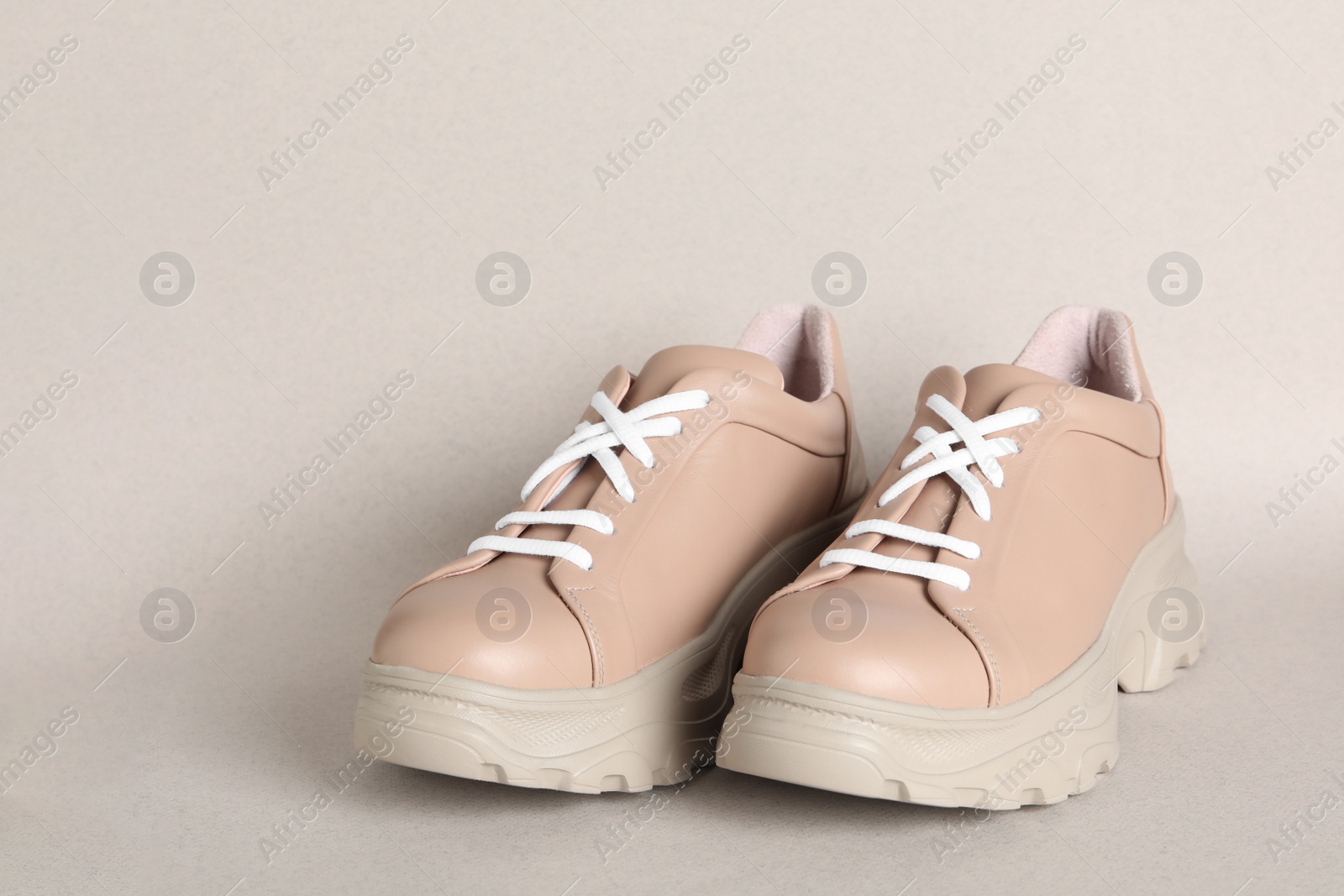 Photo of Pair of stylish shoes with white laces on beige background