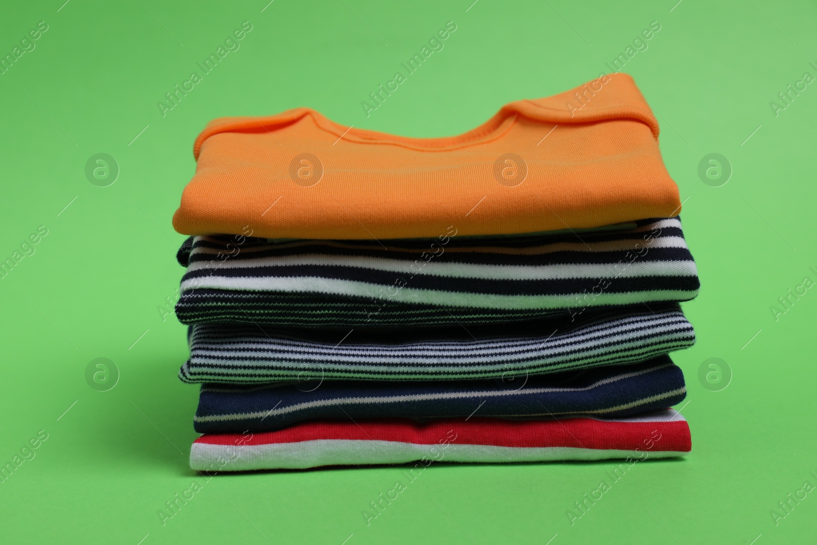Photo of Stack of clean baby clothes on light green background