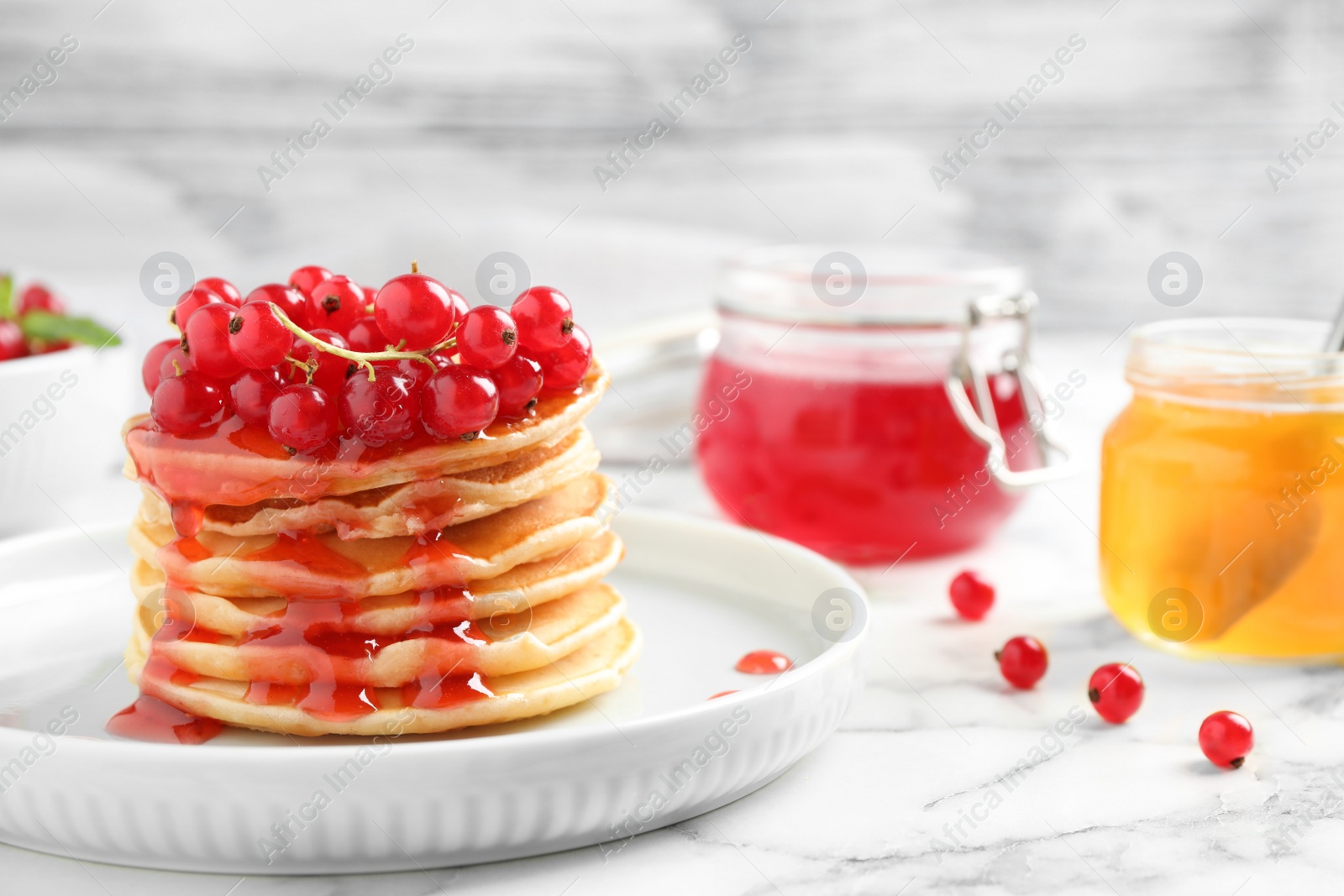 Photo of Delicious pancakes with fresh berries and syrup on marble table