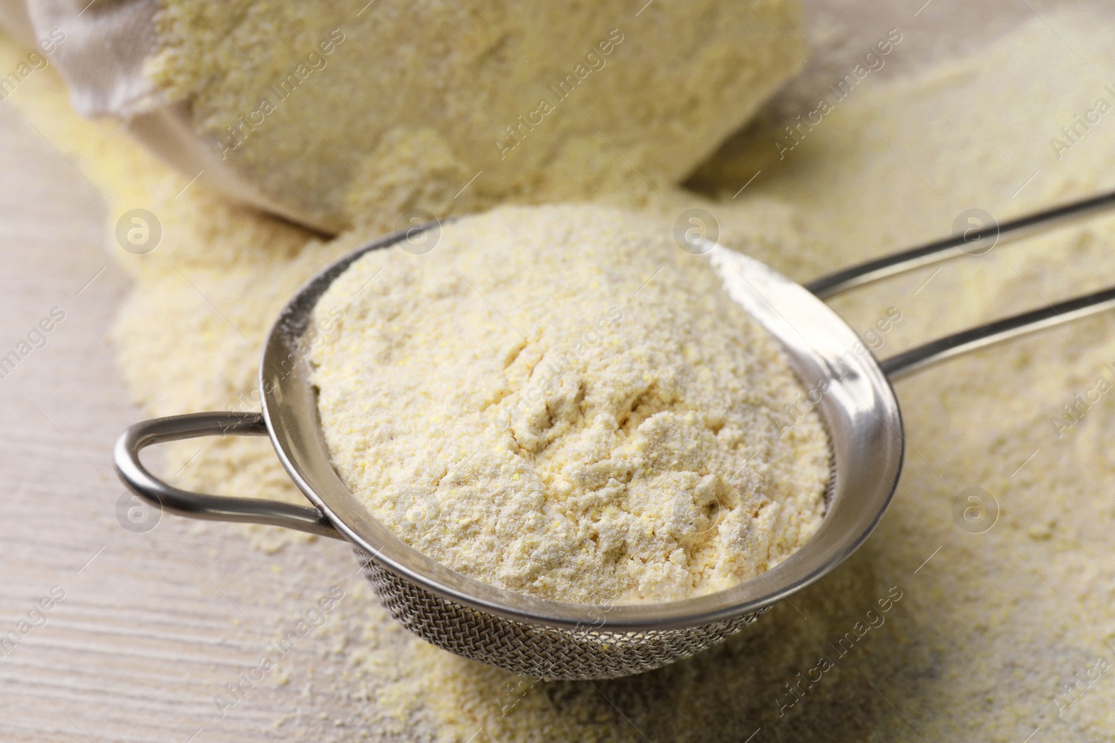 Photo of Sieve with quinoa flour on wooden table, closeup