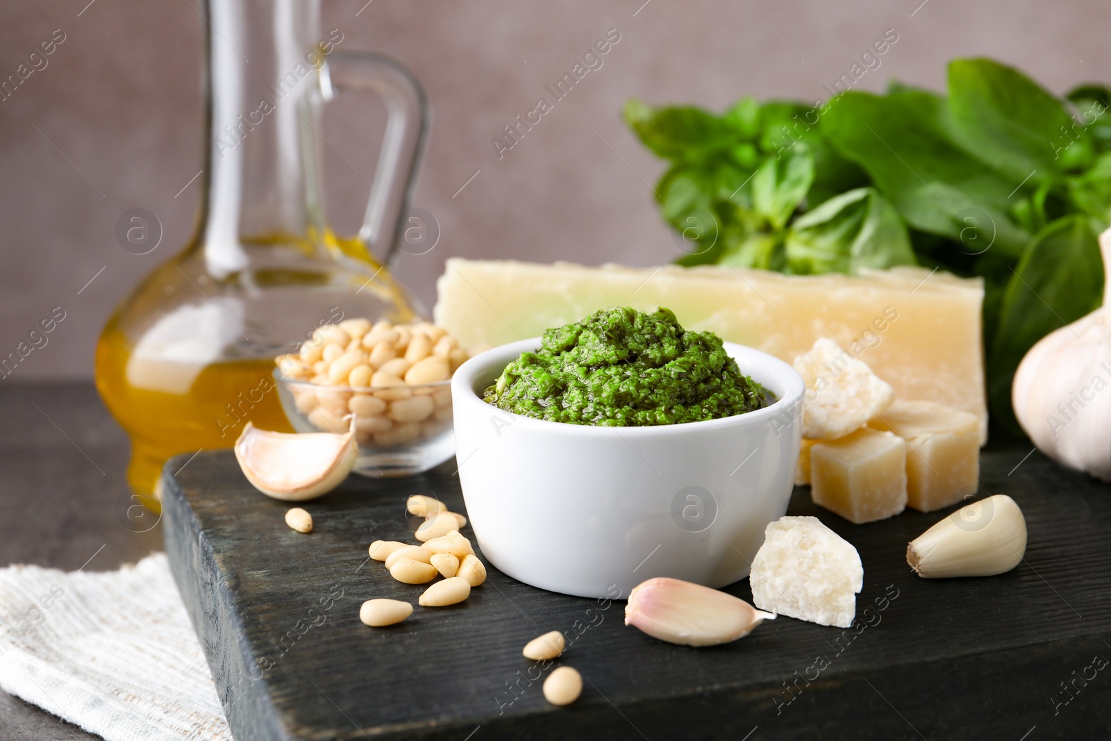 Photo of Board with bowl of pesto sauce and ingredients on table. Space for text