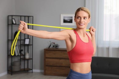 Athletic woman doing exercise with fitness elastic band at home