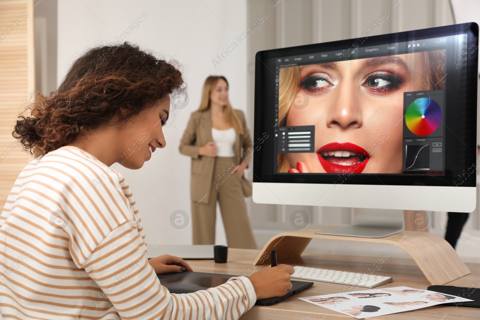 Photo of Professional African American retoucher working with graphic tablet at desk in photo studio