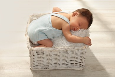 Photo of Cute newborn baby sleeping in white wicker basket indoors