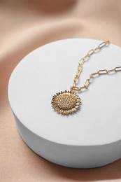 Photo of Stylish presentation of elegant necklace on beige cloth, closeup