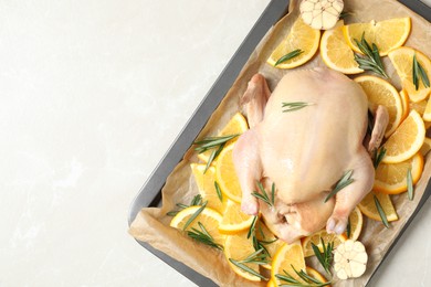 Photo of Chicken with orange, rosemary and garlic in baking tray on light table, top view. Space for text