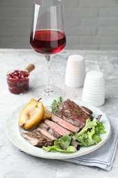 Delicious roasted beef meat, caramelized pear and greens served on light table