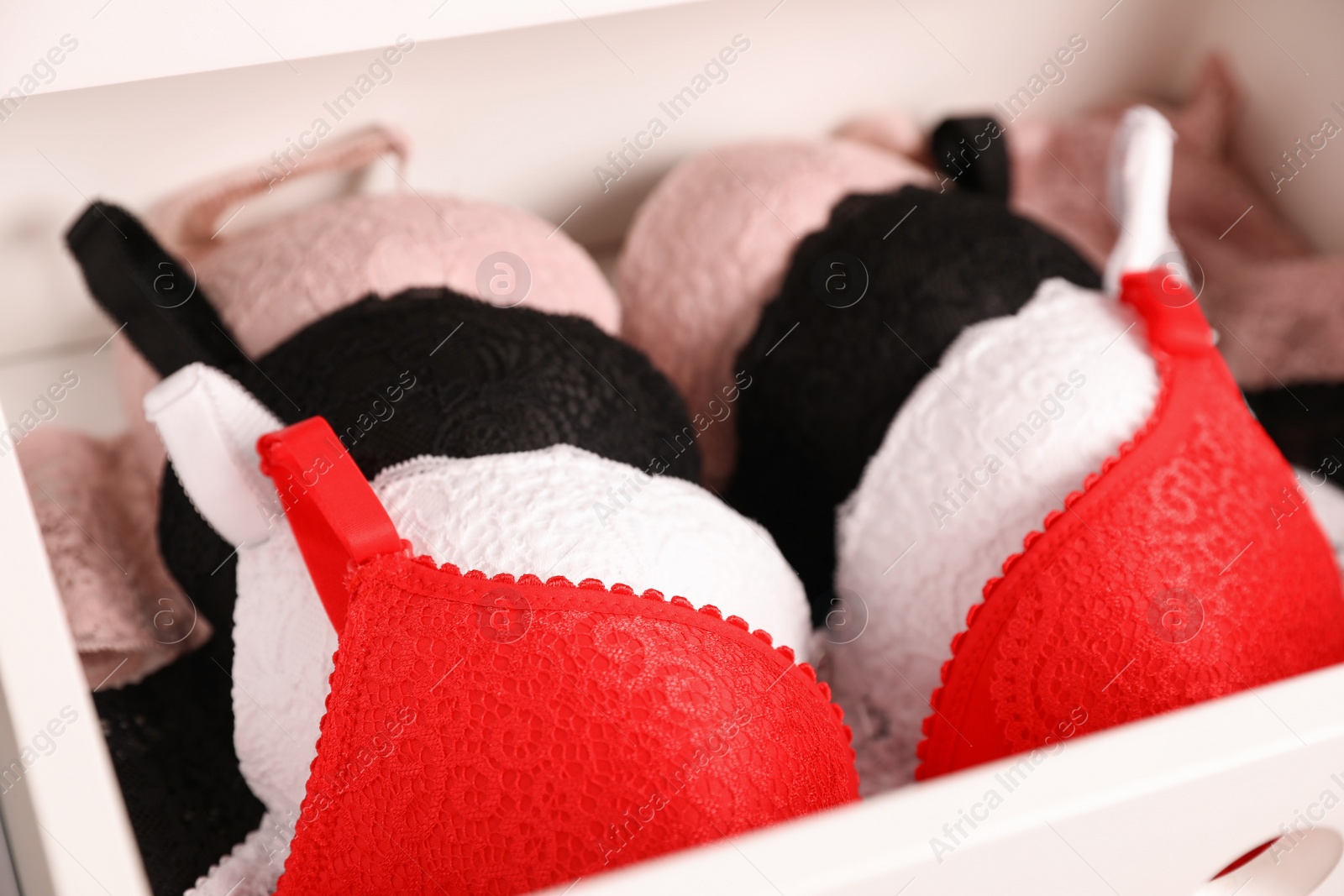 Photo of Drawer with beautiful lace bras, closeup. Stylish underwear