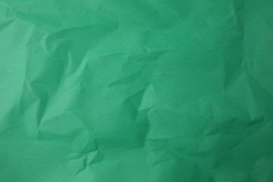 Photo of Sheet of crumpled green paper as background, top view