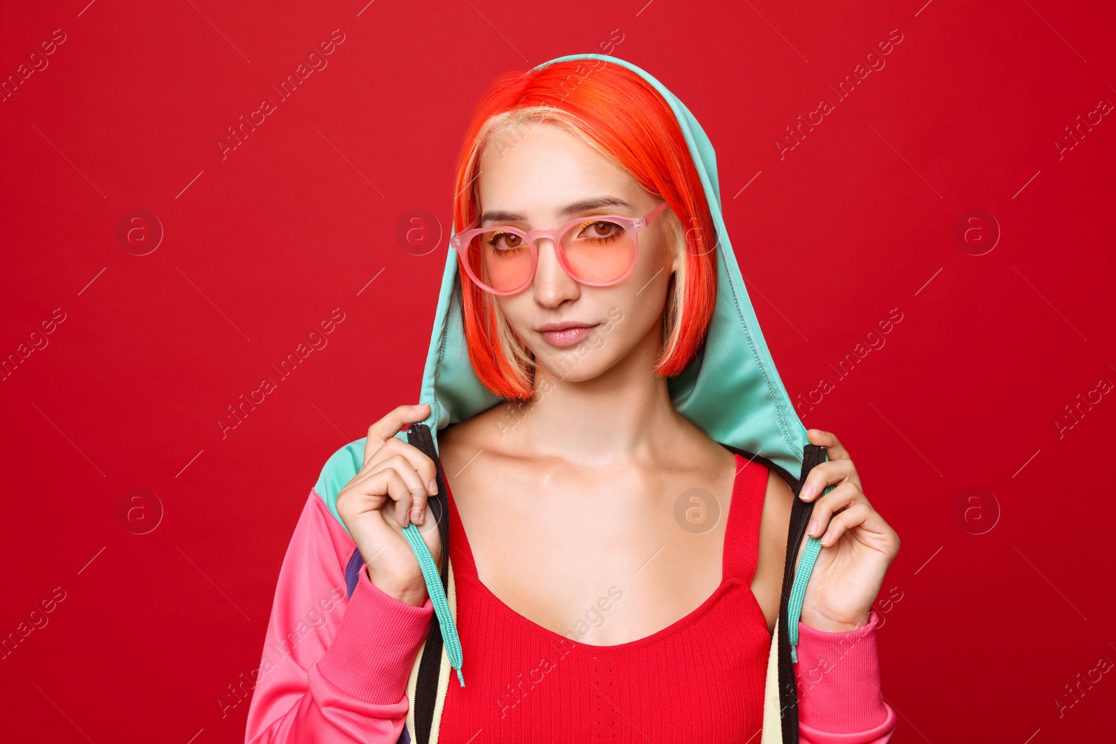 Photo of Beautiful young woman with bright dyed hair on red background