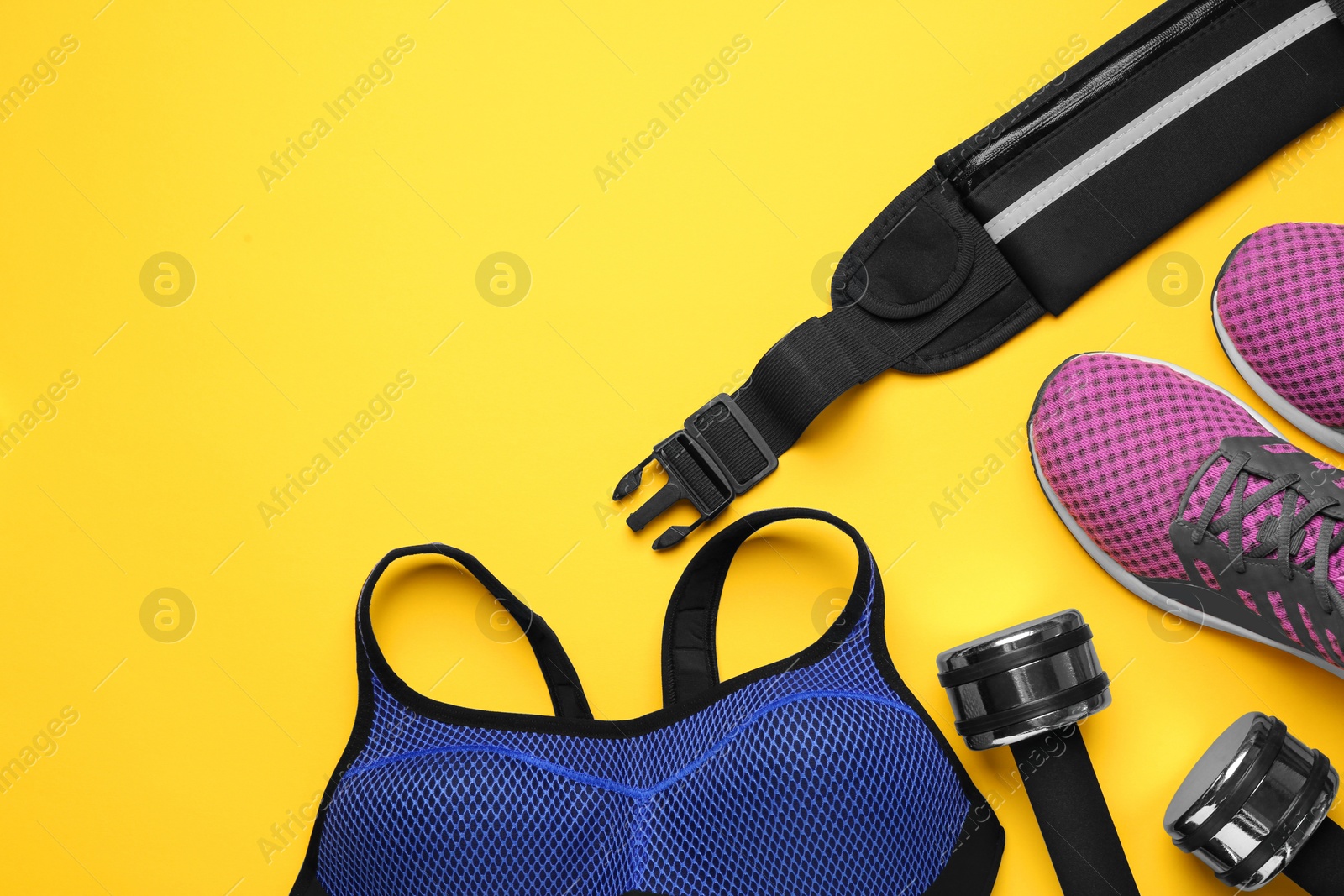 Photo of Flat lay composition with stylish black waist bag on yellow background, space for text